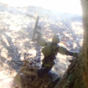 Space soldier leaning against tree on a branch looking below with gun raised upwards